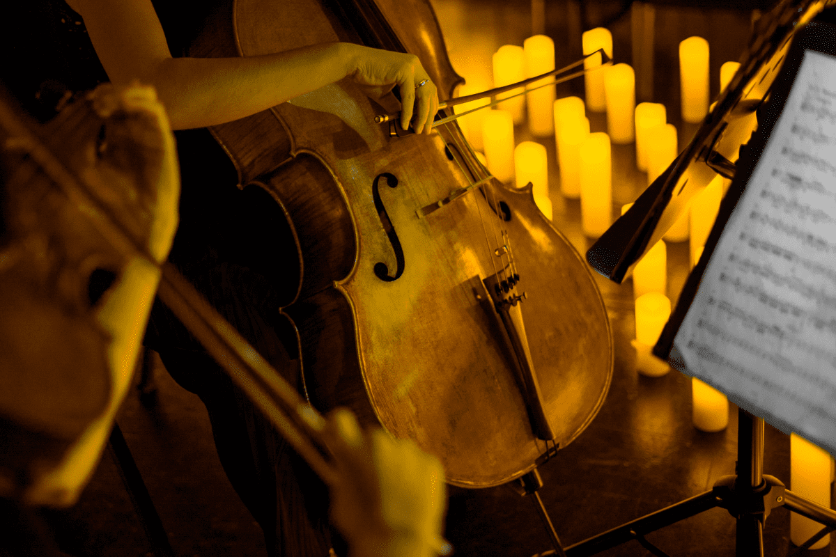 A close up shot of a cello surrounded by candles