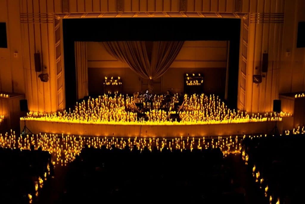 A wide shot of a string quartet performing on stage surrounded by candles at BOK Auditorium
