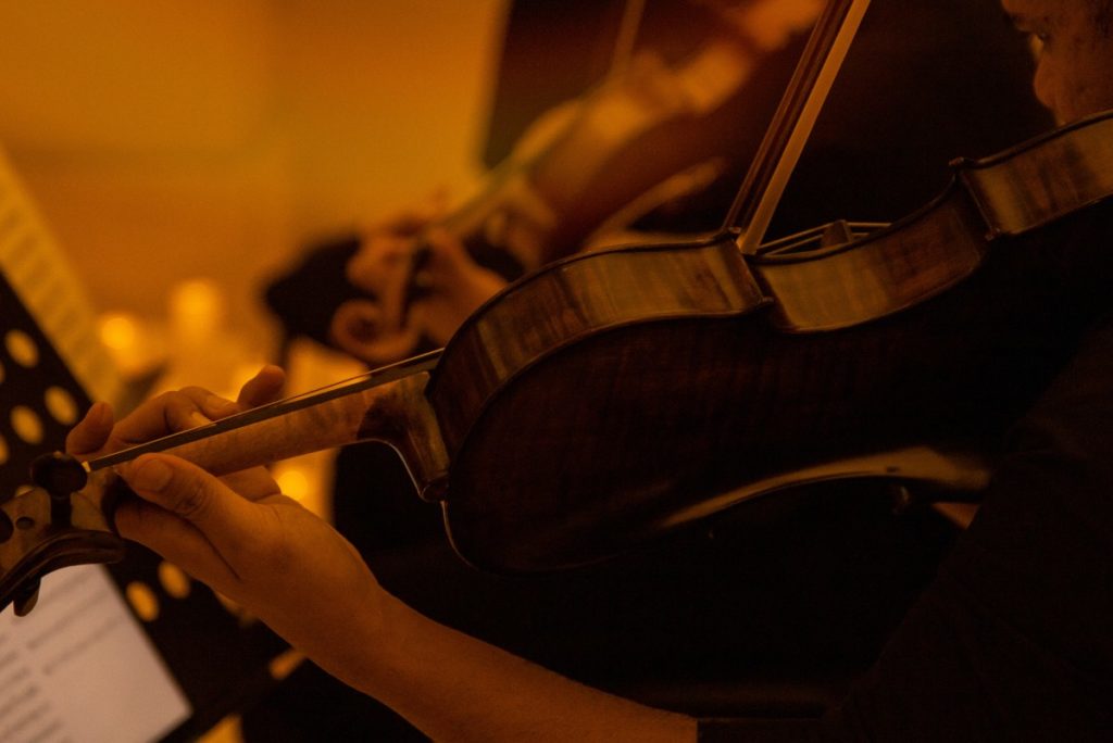 A tight shot of a musician playing the violin taken from the back