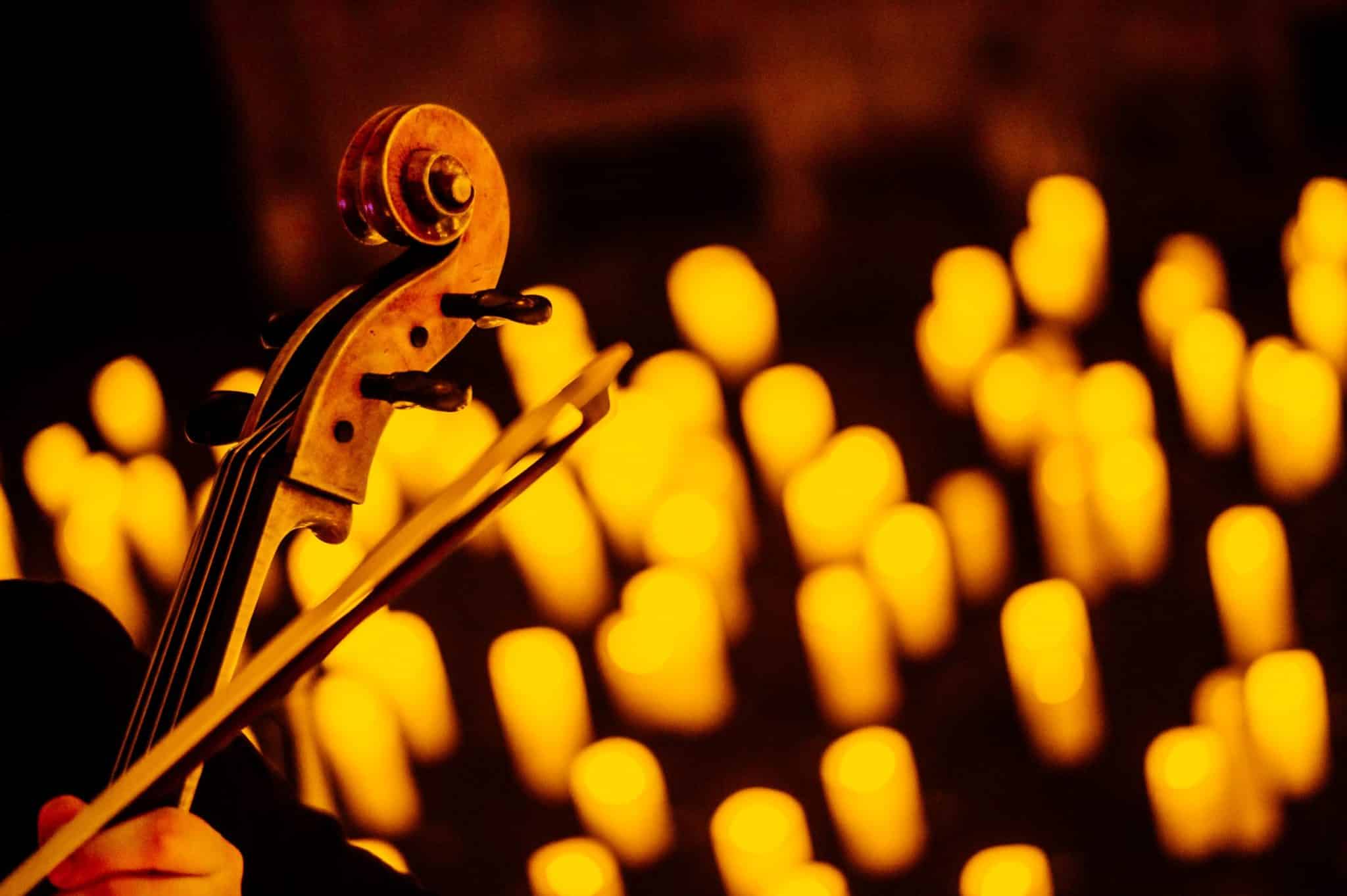 A close-up of the top of a violin with candles in the background.